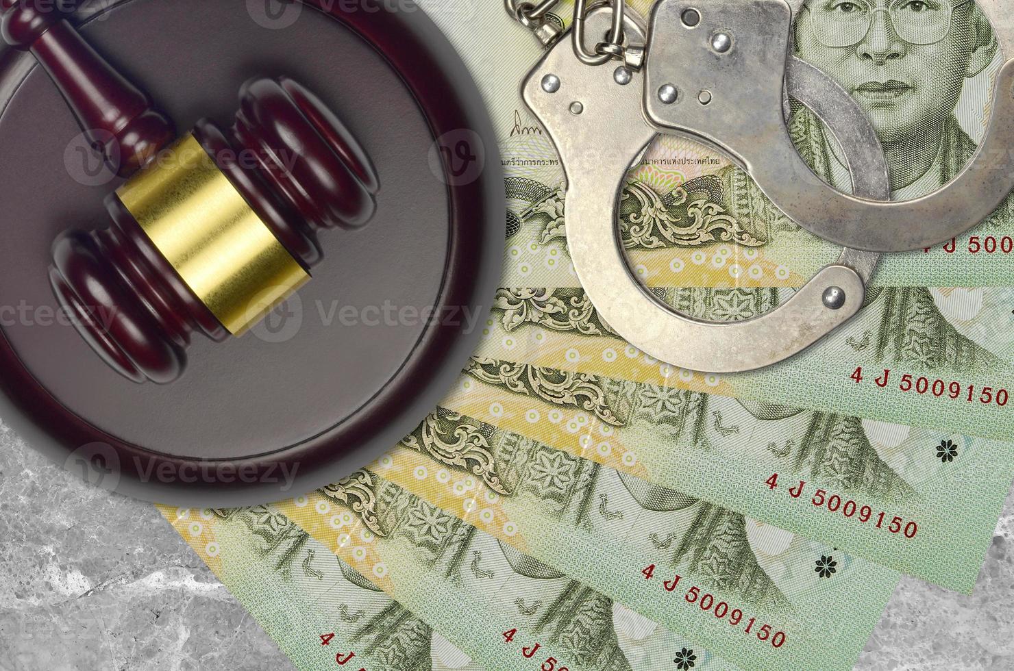 20 Thai Baht bills and judge hammer with police handcuffs on court desk. Concept of judicial trial or bribery. Tax avoidance photo
