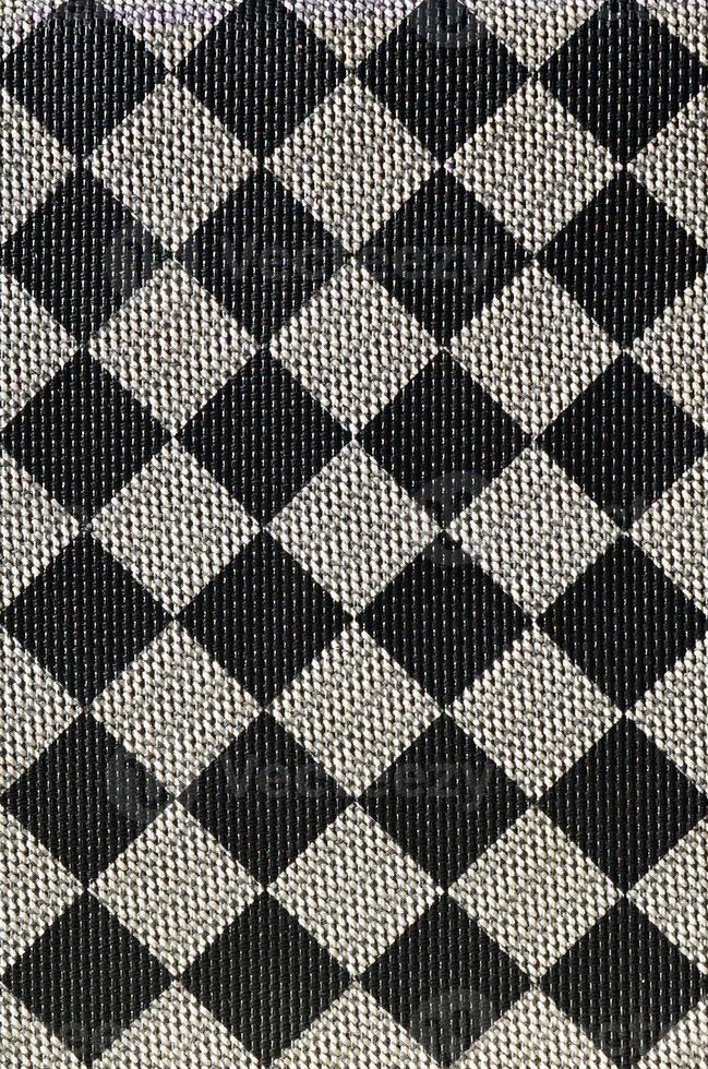 Plastic texture in the form of a very small cloth binding, painted in black and gray in the style of a chessboard. Macro shot photo