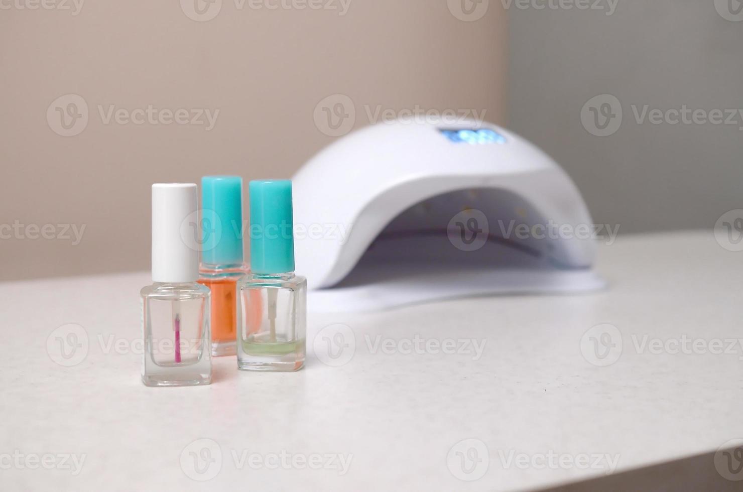 luces de lámpara de diodo uv para uñas y juego de esmalte de uñas cosmético para manicura y pedicura sobre fondo de mesa blanco foto