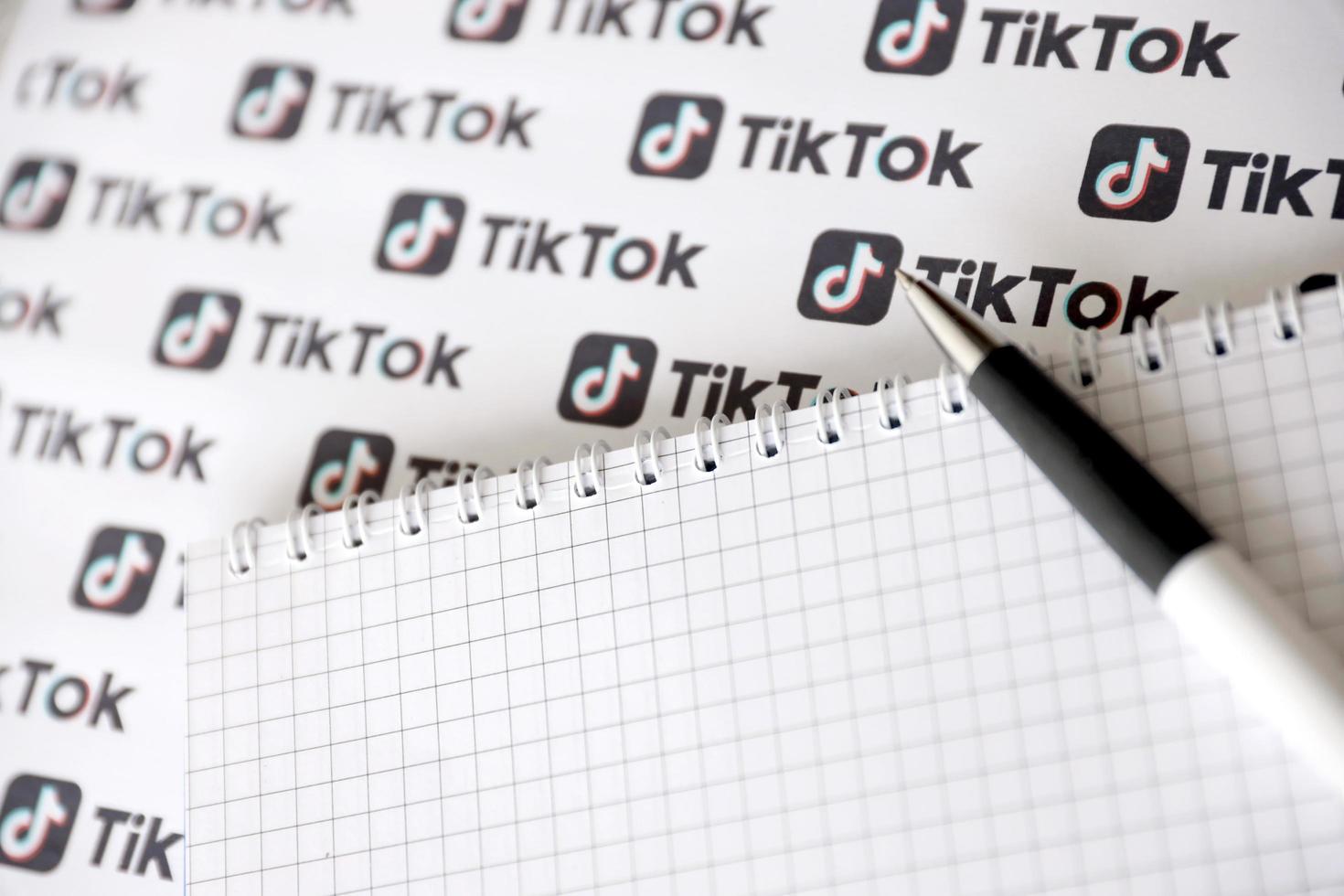 ternopil, ucrania - 2 de mayo de 2022 bloc de notas con bolígrafo y muchos logotipos de tiktok impresos en papel. tiktok o douyin es un famoso servicio chino de alojamiento de videos de formato corto propiedad de bytedance foto