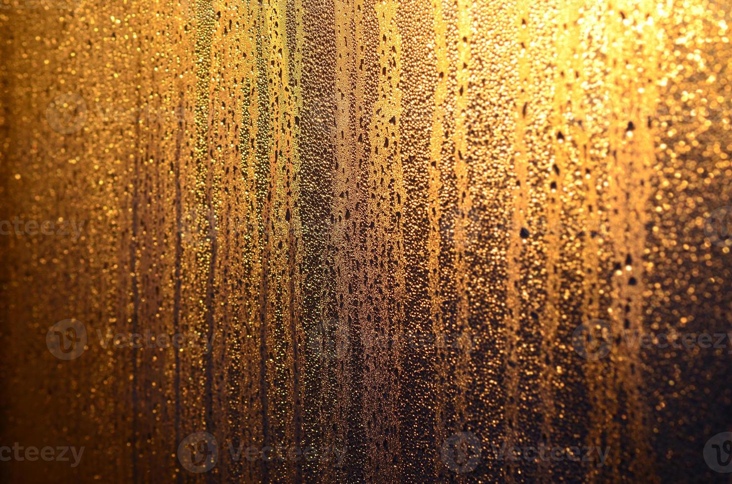 The texture of misted glass with a lot of drops and drips of condensation against the sunlight at dawn. Background image photo