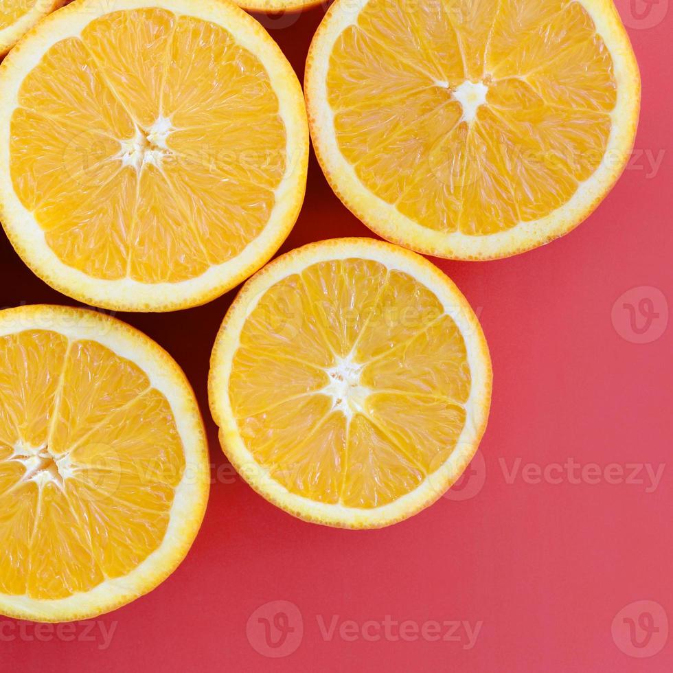 Top view of a several orange fruit slices on bright background in red color. A saturated citrus texture image photo