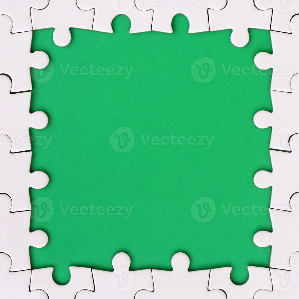 Framing in the form of a rectangle, made of a white jigsaw puzzle around the green space photo