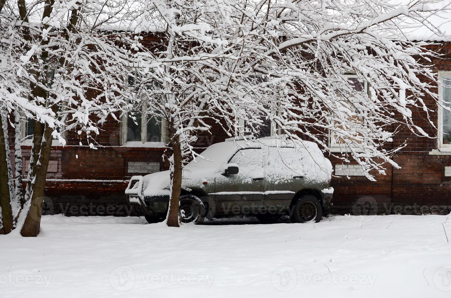 Photo of a car covered in a thick layer of snow. Consequences of heavy snowfall