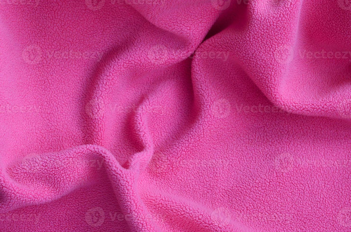 The blanket of furry pink fleece fabric. A background of light pink soft plush fleece material with a lot of relief folds photo