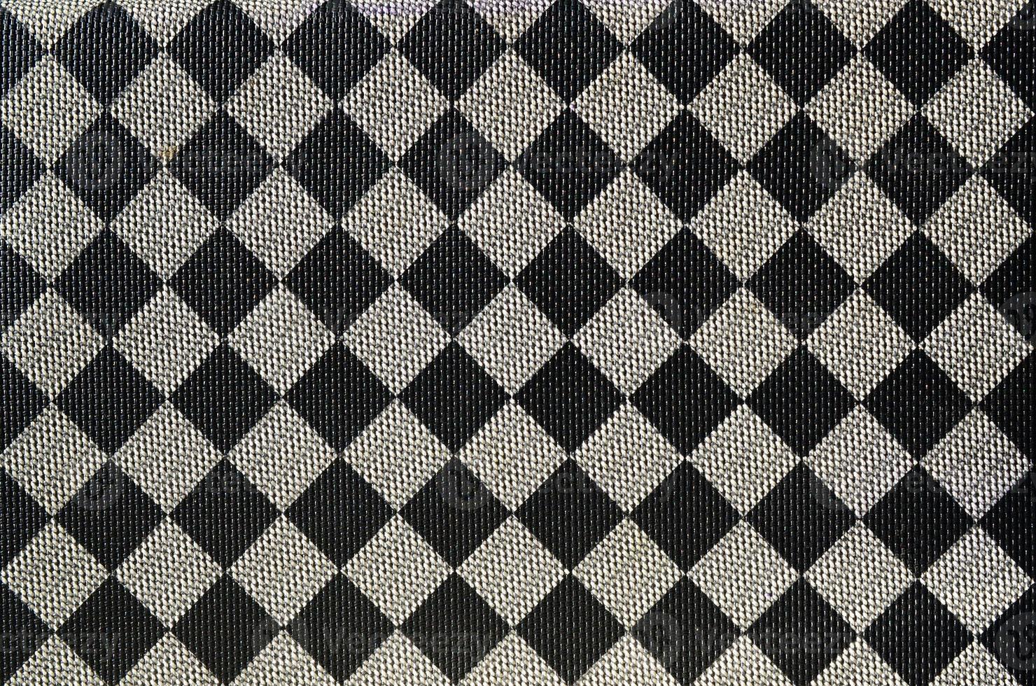 Plastic texture in the form of a very small cloth binding, painted in black and gray in the style of a chessboard. Macro shot photo