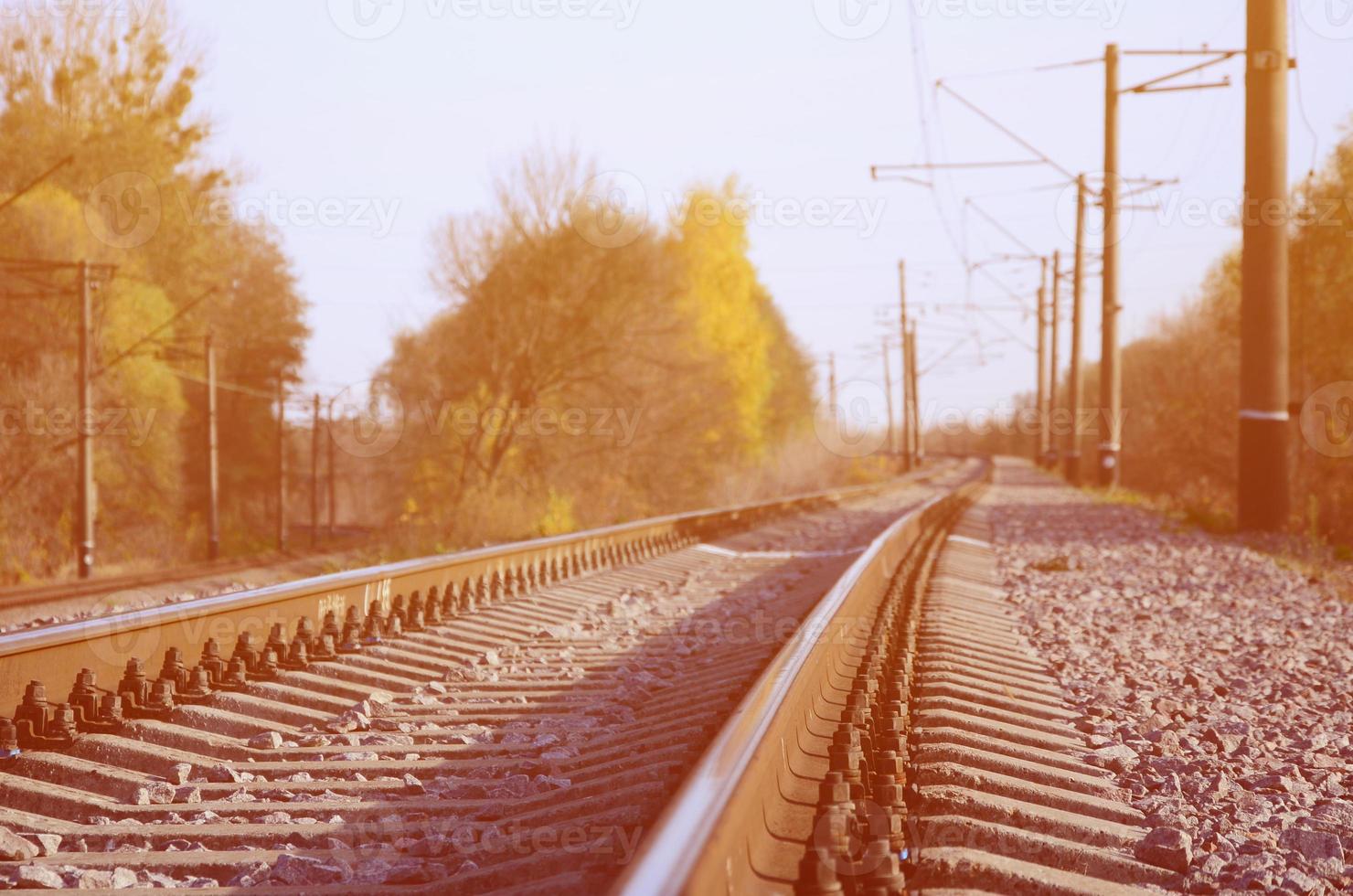 Autumn industrial landscape. Railway receding into the distance among green and yellow autumn trees photo