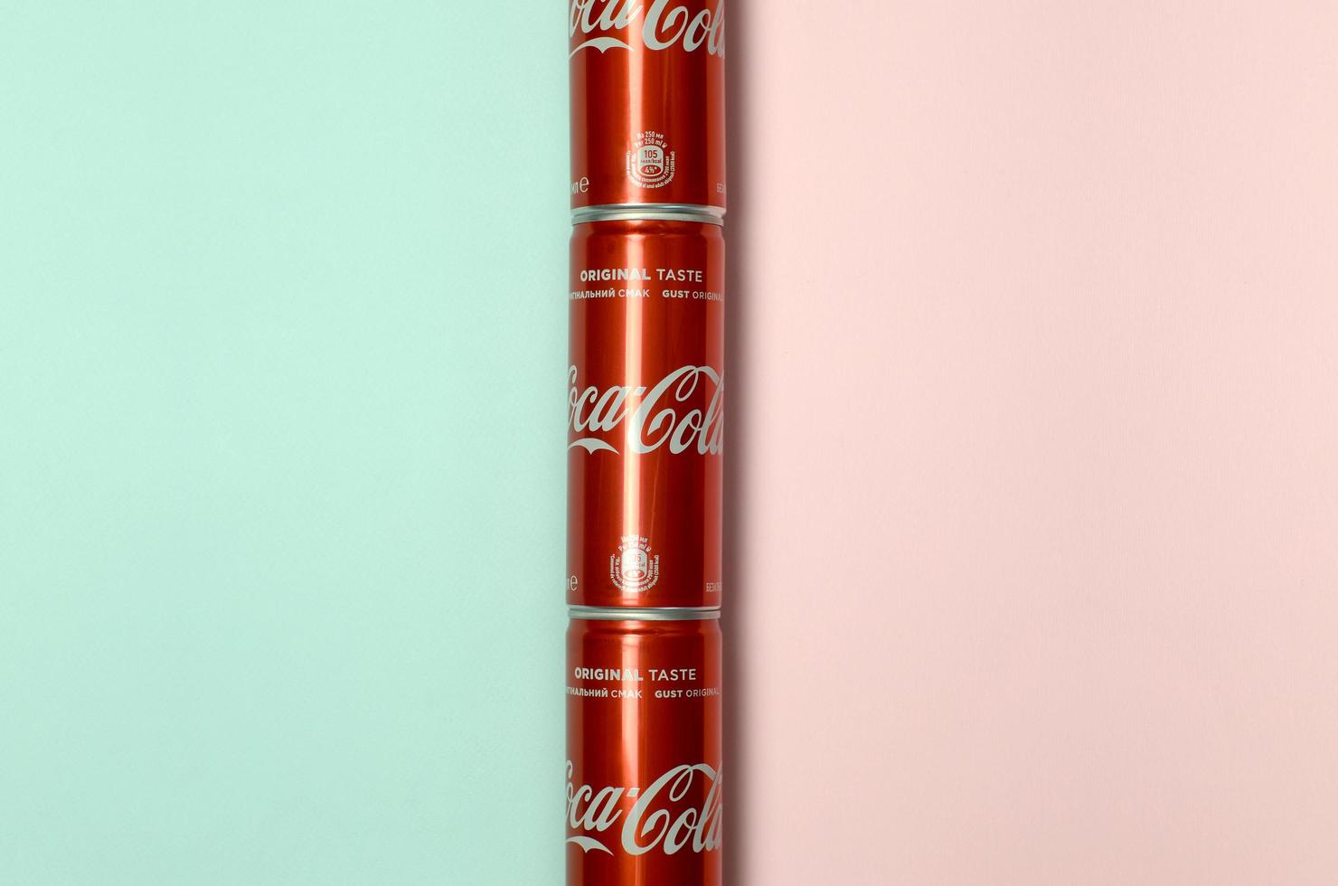 KHARKOV. UKRAINE - MAY 2, 2019 Flat lay shot carbonated red drink tin cans Coca Cola laying on pastel blue and coral background photo