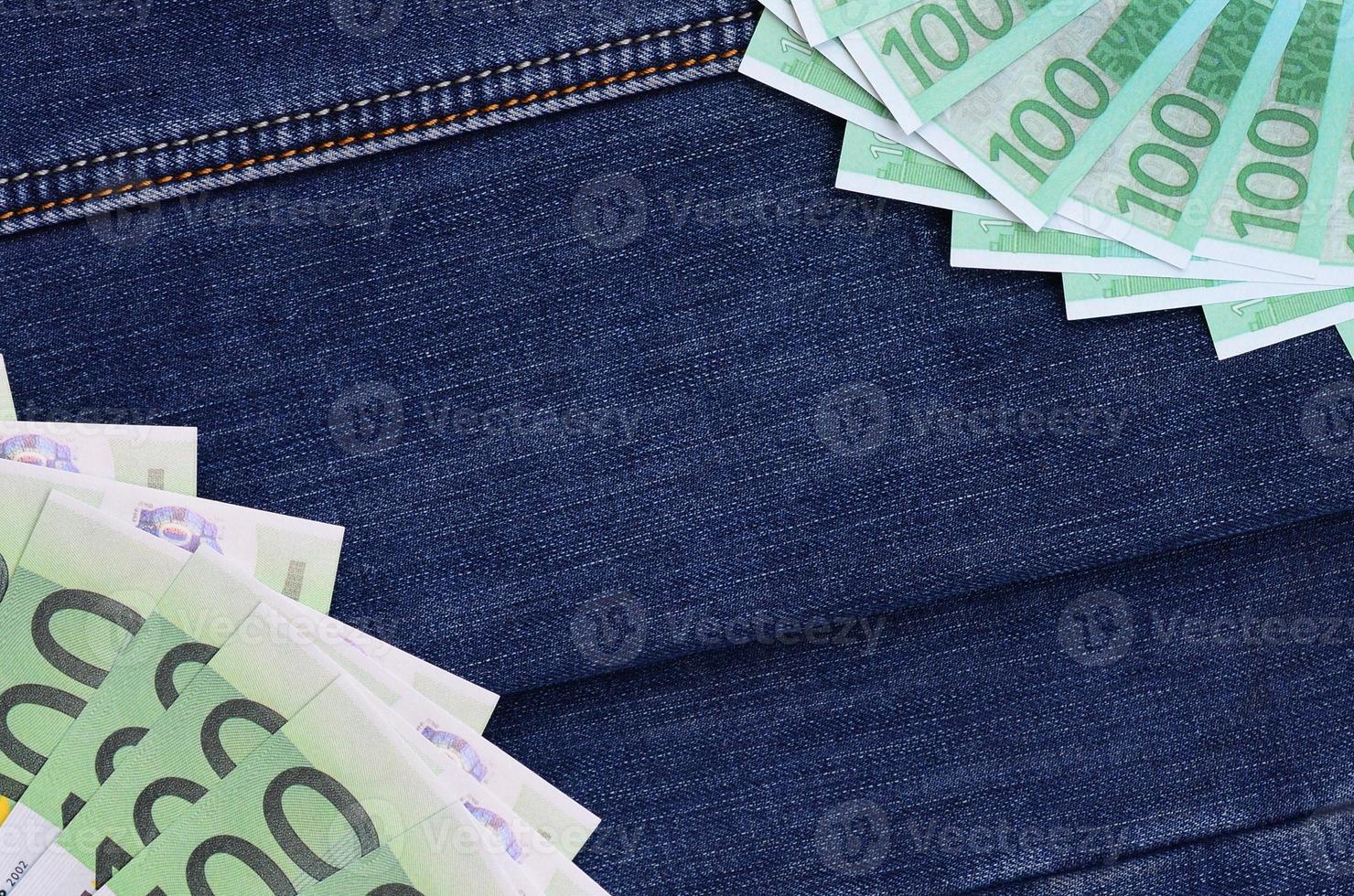 The fan of a lot of euro bills is on a dark denim surface. Background image photo