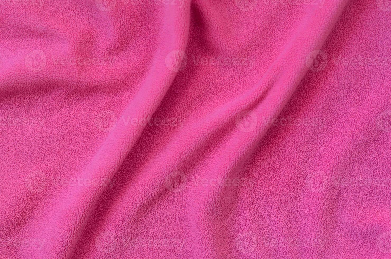 The blanket of furry pink fleece fabric. A background of light pink soft plush fleece material with a lot of relief folds photo