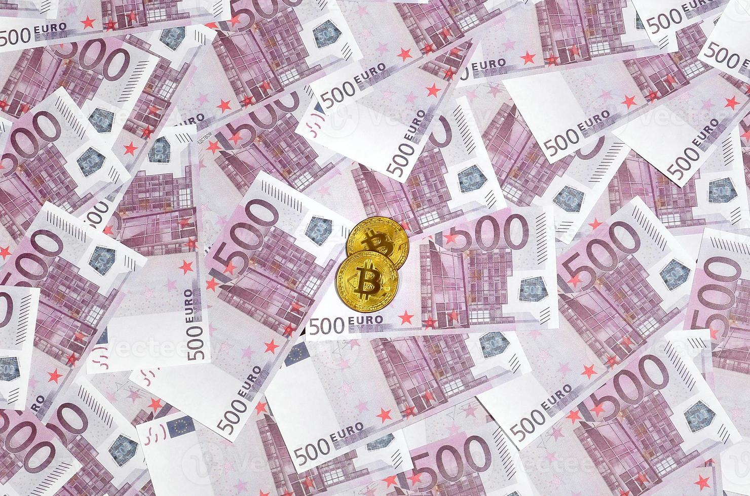 Bitcoins over pile of five hundred euro banknotes. Traditional money versus cryptocurrency concept. Gold coin above 500 euro bills. Close up photo