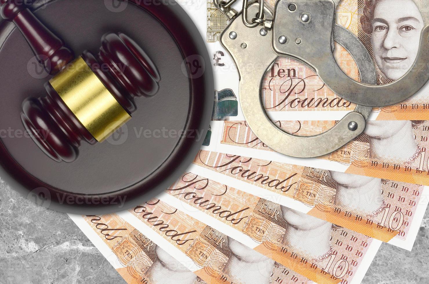 10 British pounds bills and judge hammer with police handcuffs on court desk. Concept of judicial trial or bribery. Tax avoidance photo