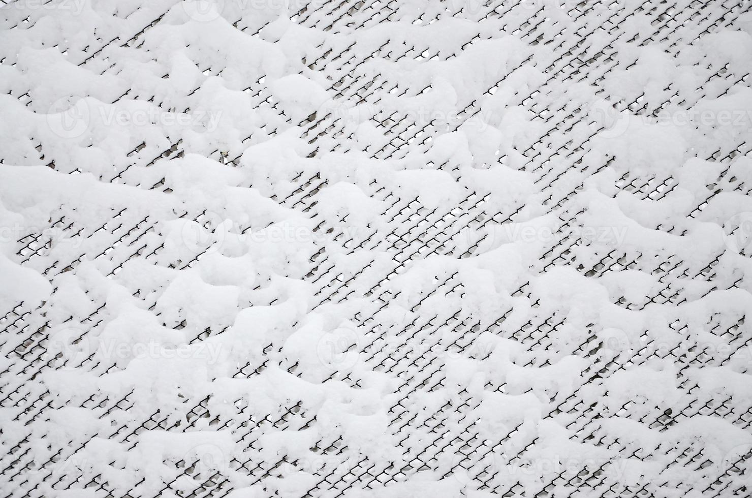 Close-up metal mesh covered with a thick layer of snow in the cells photo