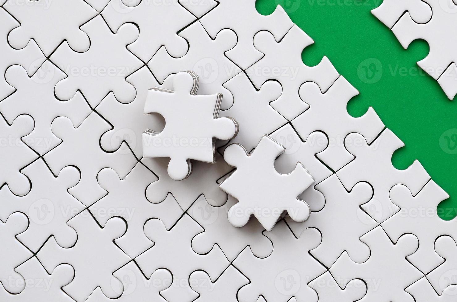 The green path is laid on the platform of a white folded jigsaw puzzle. The missing elements of the puzzle are stacked nearby. Texture image with space for text photo