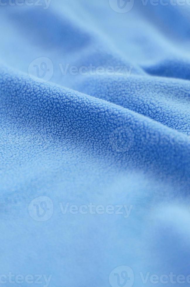 The blanket of furry blue fleece fabric. A background of light blue soft plush fleece material with a lot of relief folds photo