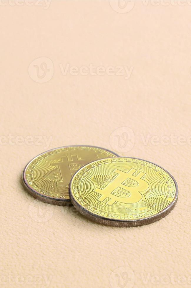 Two golden bitcoins lies on a blanket made of soft and fluffy light orange fleece fabric. Physical visualization of virtual crypto currency photo