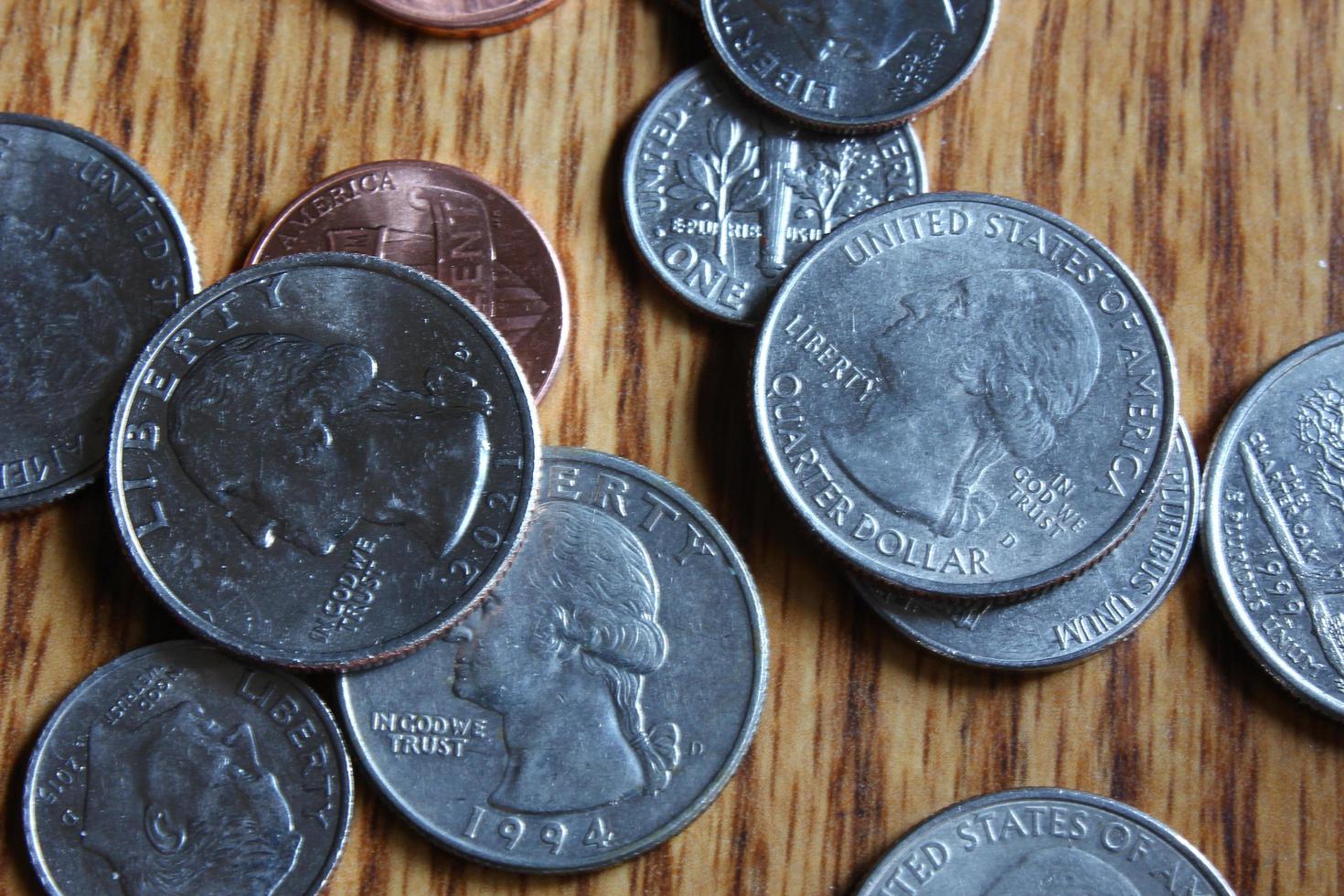 monedas de dólar esparcidas sobre una mesa de madera, monedas de dólar planas. foto