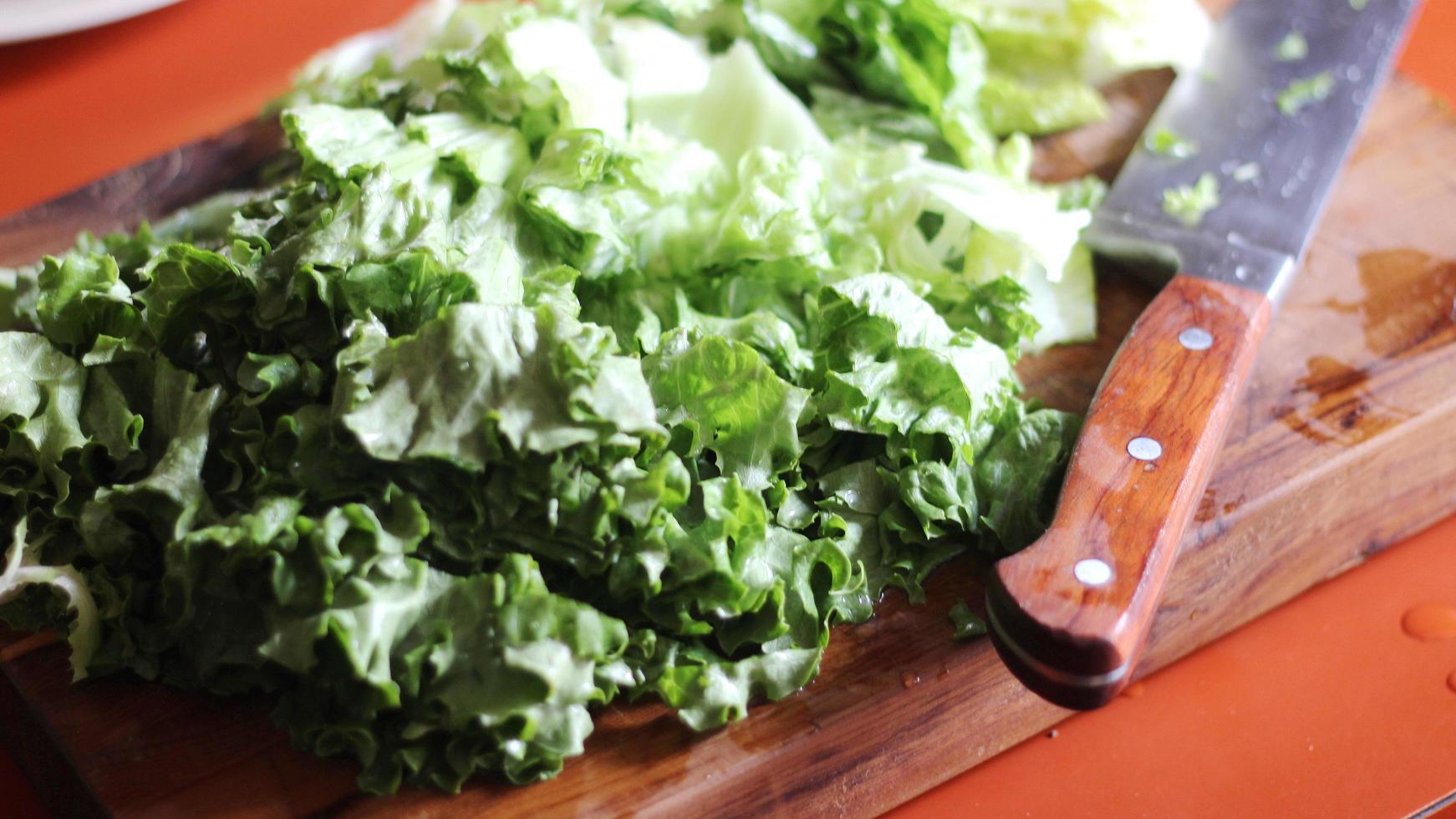 Vegetables cut on a wooden cutting board with a knife. photo