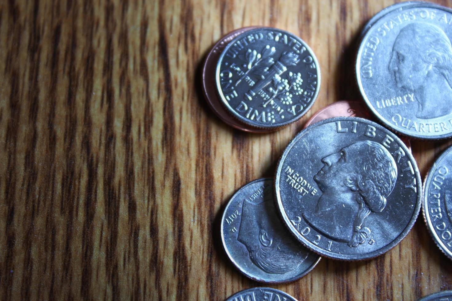 monedas de dólar y billetes de dólar esparcidos sobre una mesa de madera, monedas de dólar planas. foto