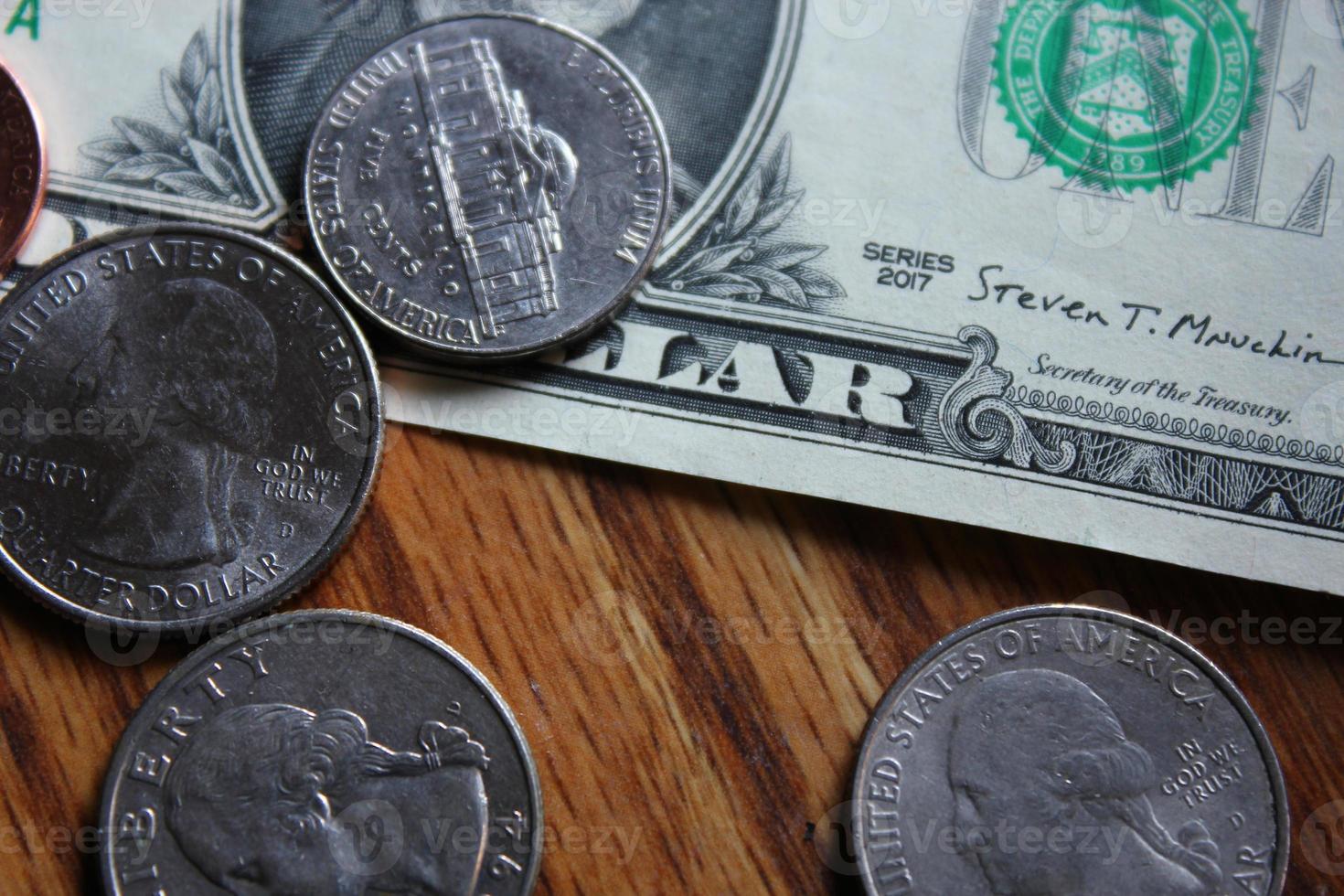 Dollar coins and dollar bills scattered on a wooden table, flat lay dollar coins. photo