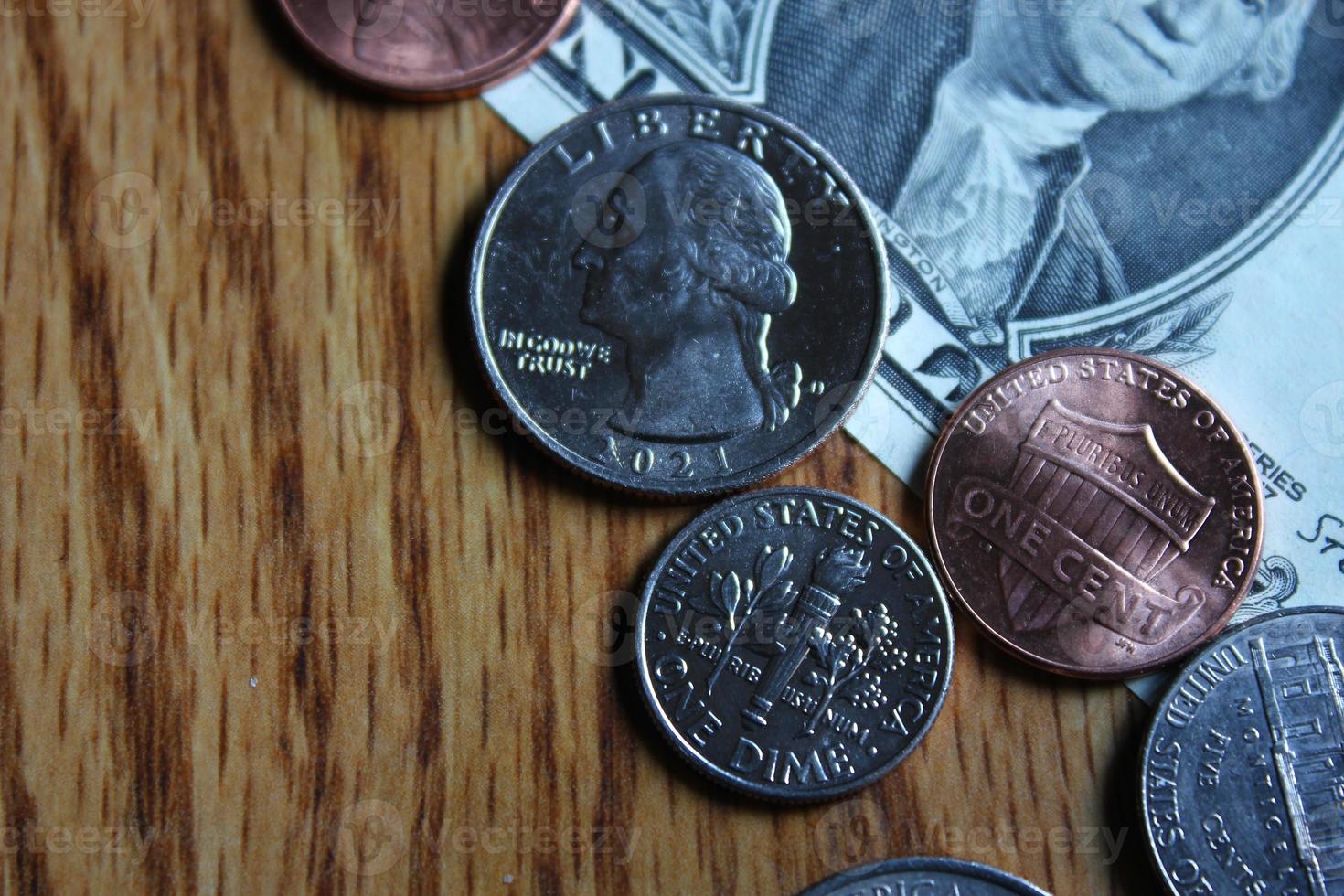 monedas de dólar y billetes de dólar esparcidos sobre una mesa de madera, monedas de dólar planas. foto