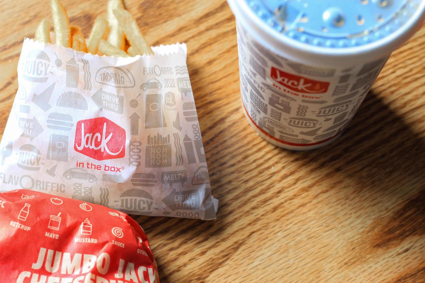 WASHINGTON, USA - MARCH, 15 2022  Jack in the box hamburgers, french fries and glasses served on a brown wooden table. photo