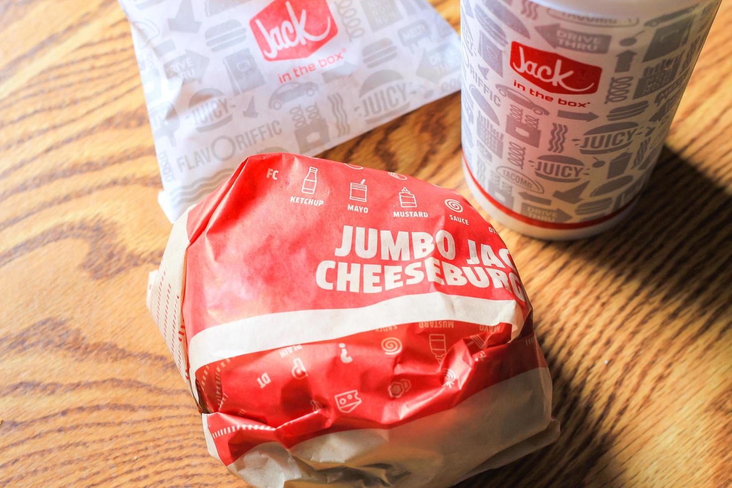WASHINGTON, USA - MARCH, 15 2022  Jack in the box hamburgers, french fries and glasses served on a brown wooden table. photo