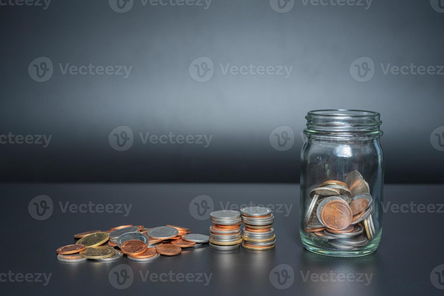 Thailand coins in jar with heap coins on black background with space photo