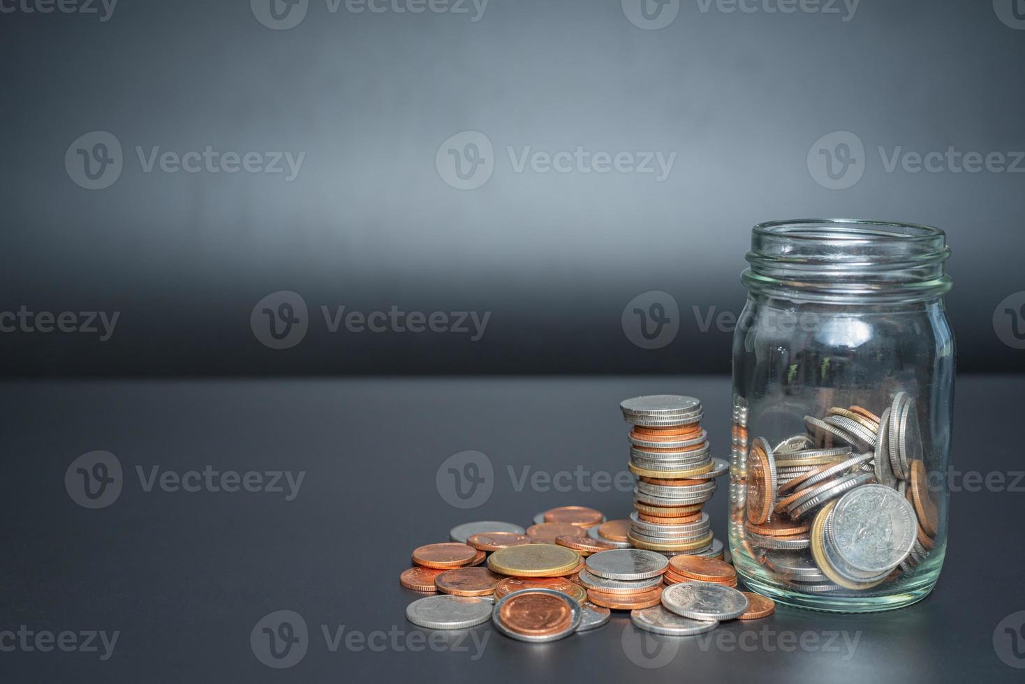 Thailand coins in jar with heap coins on black background with space photo