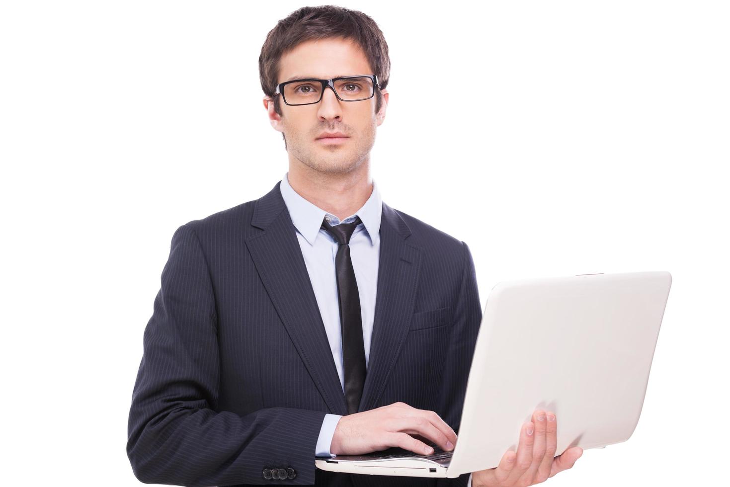 Providing the best quality support. Handsome young man in formalwear working on laptop while standing isolated on white background photo