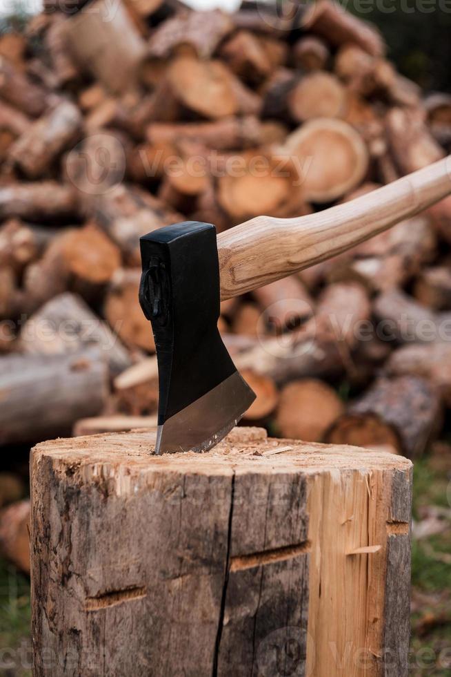 Ready for cutting timber. Close-up of axe cutting log while other logs laying in the background photo