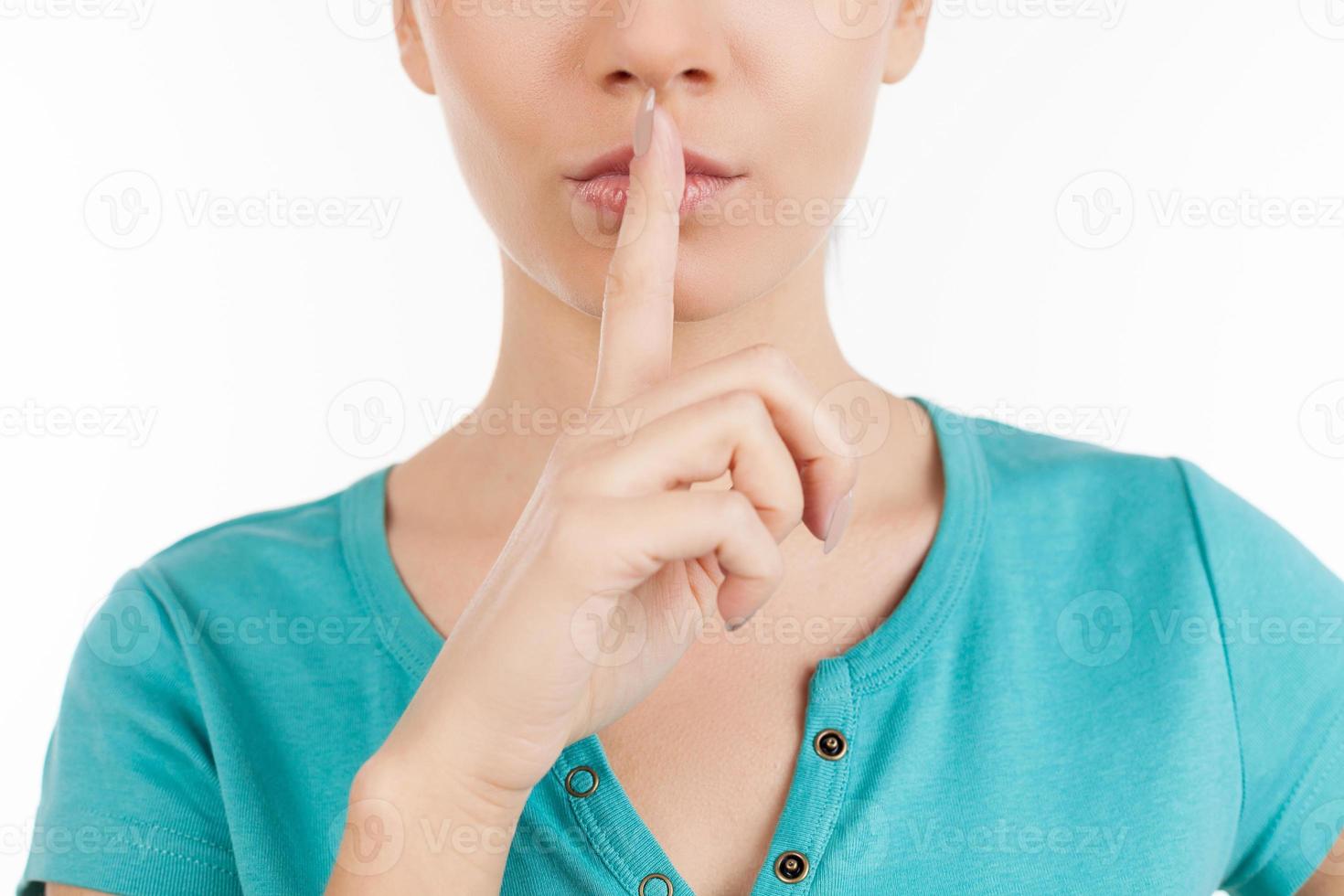 Keep silence. Cropped image of young woman holding finger on lips while isolated on white photo