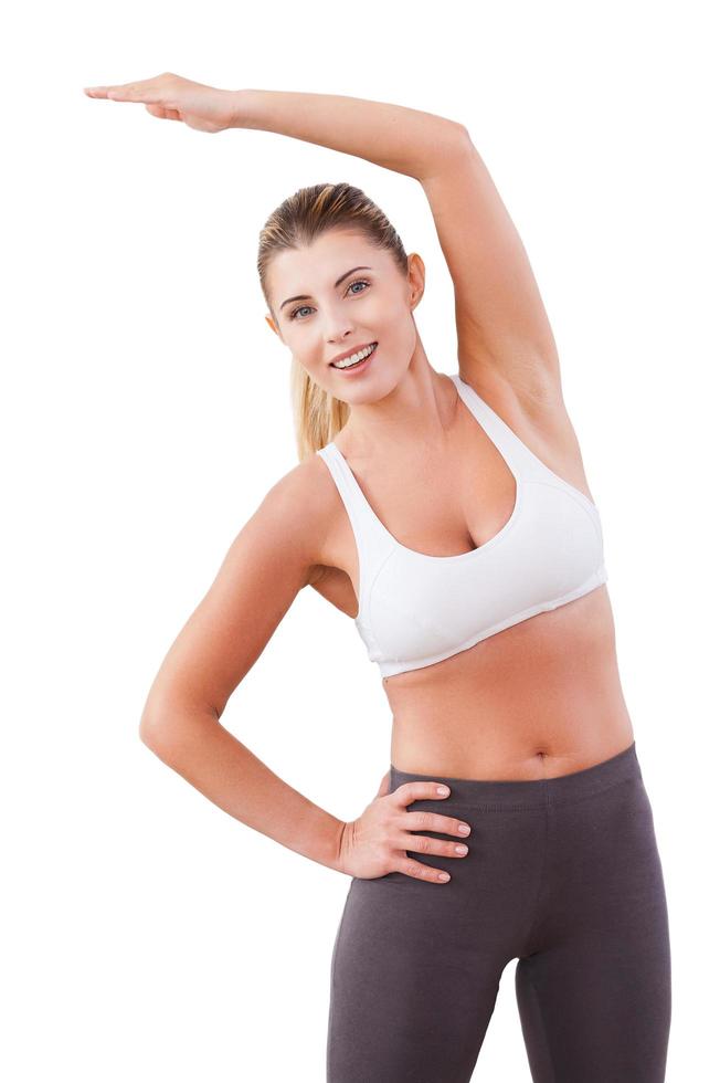 Warming up before training. Attractive mature woman exercising while standing isolated on white photo