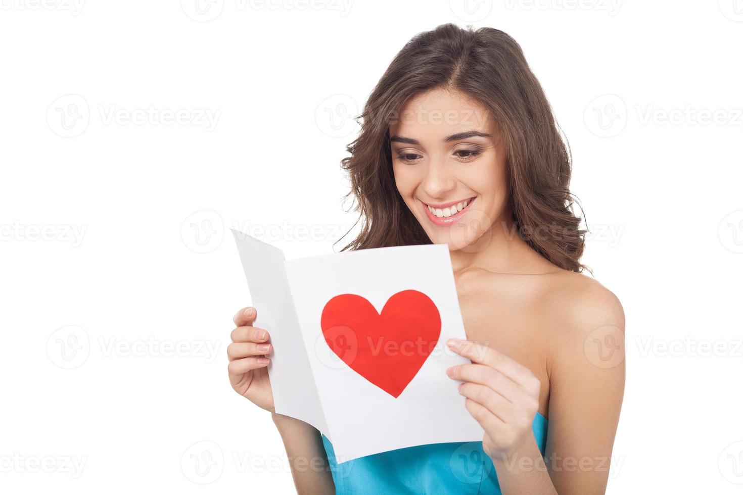Reading a Valentine card. Attractive young woman reading a valentine card while standing isolated on white background photo