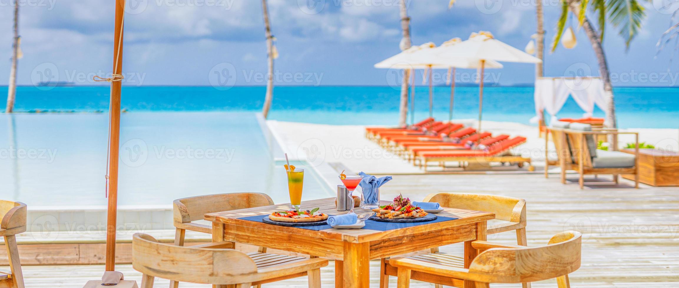 Luxury resort hotel poolside, outdoor restaurant on the beach, ocean and sky, tropical island cafe, tables, food. Summer vacation or holiday, family travel. Palm trees, infinity pool, cocktails, relax photo