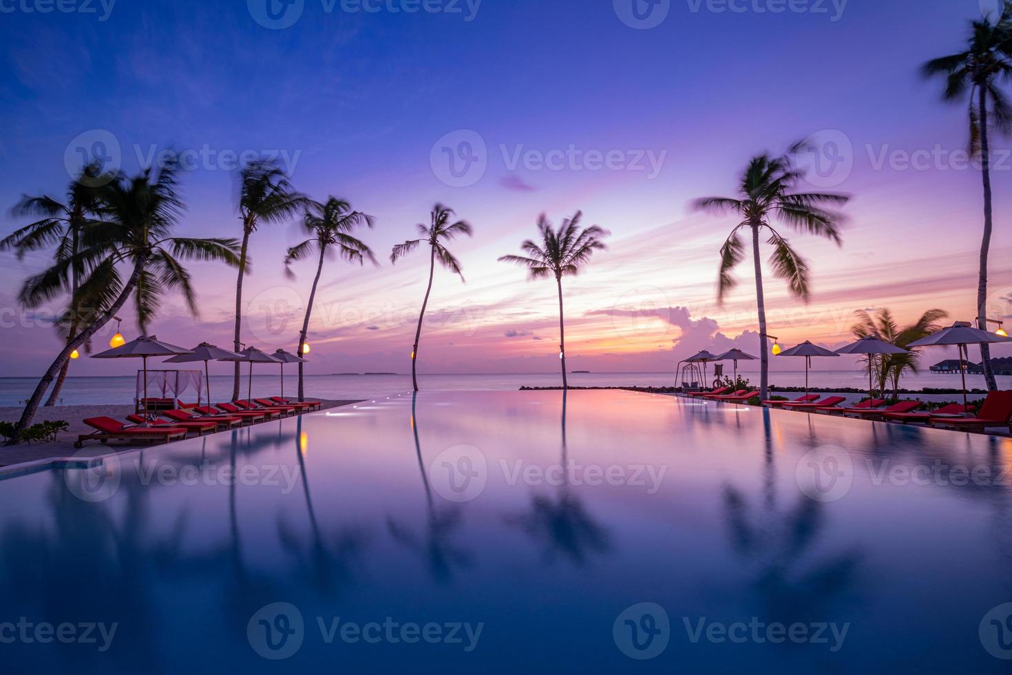 Outdoor luxury sunset over infinity pool swimming summer beachfront hotel resort, tropical landscape. Beautiful tranquil beach holiday vacation background. Amazing island sunset beach view, palm trees photo