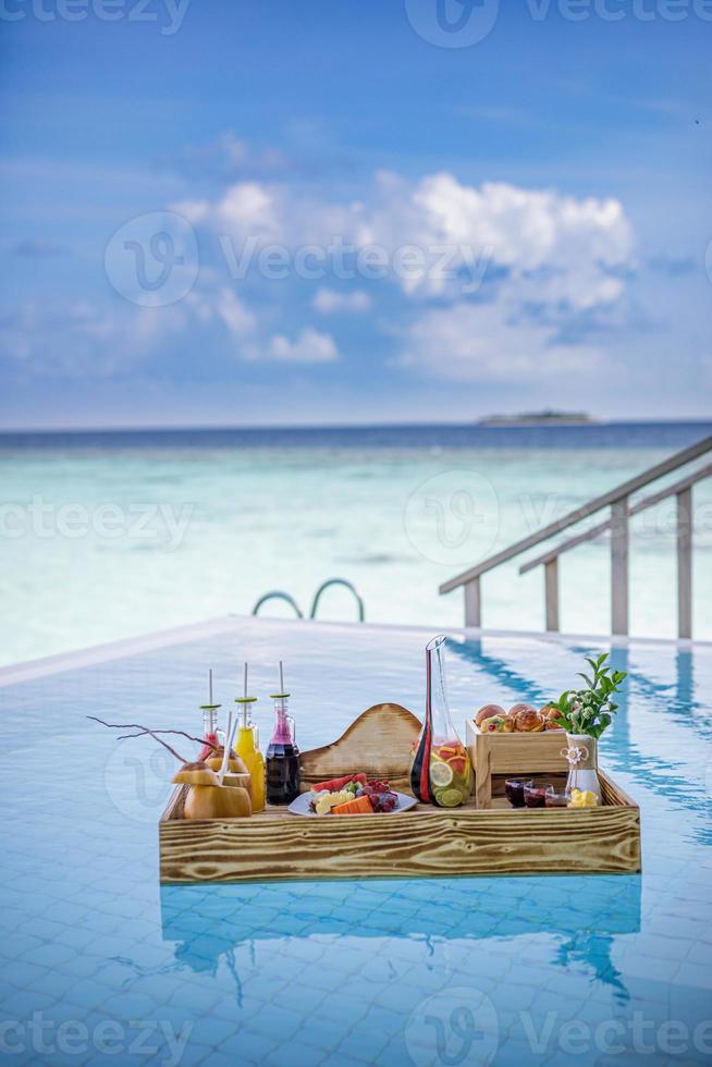 Breakfast in swimming pool, floating breakfast in luxurious tropical resort. Table relaxing on calm pool water, healthy breakfast and fruit plate by resort pool. Tropical couple beach luxury lifestyle photo