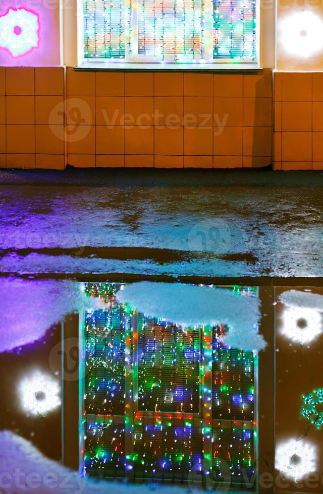 xmas illumination reflected in melting snow puddle photo