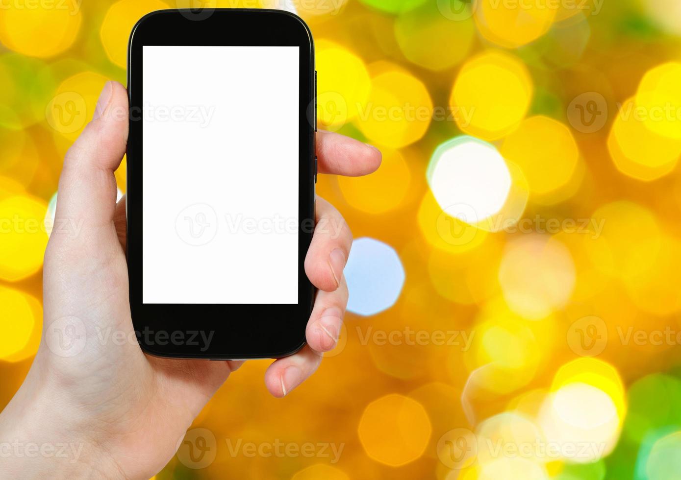 mano con smartphone en el fondo borroso de Navidad foto