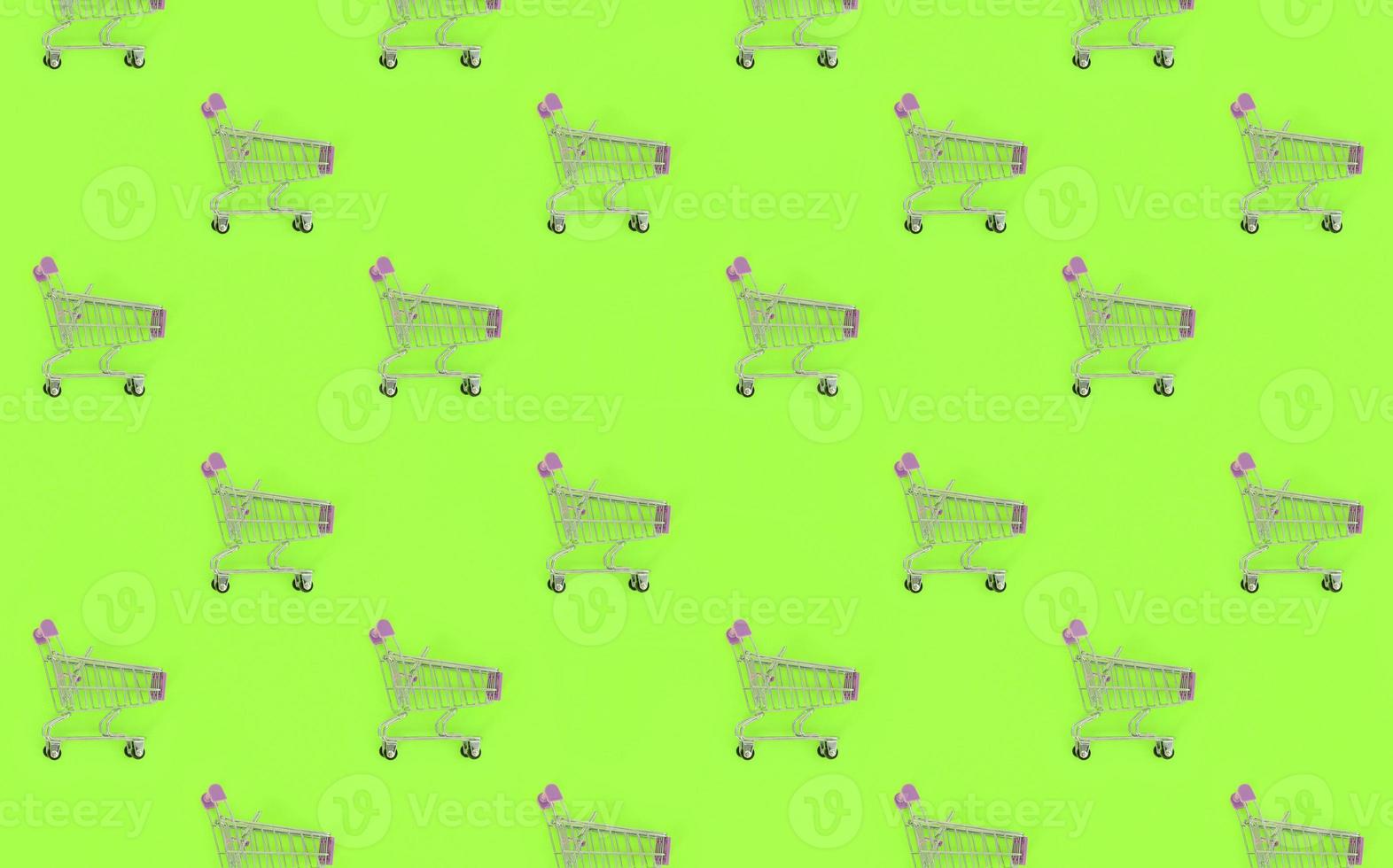 Shopping addiction, shopping lover or shopaholic concept. Many small empty shopping carts perform a pattern on a pastel colored paper background. Flat lay composition, top view photo