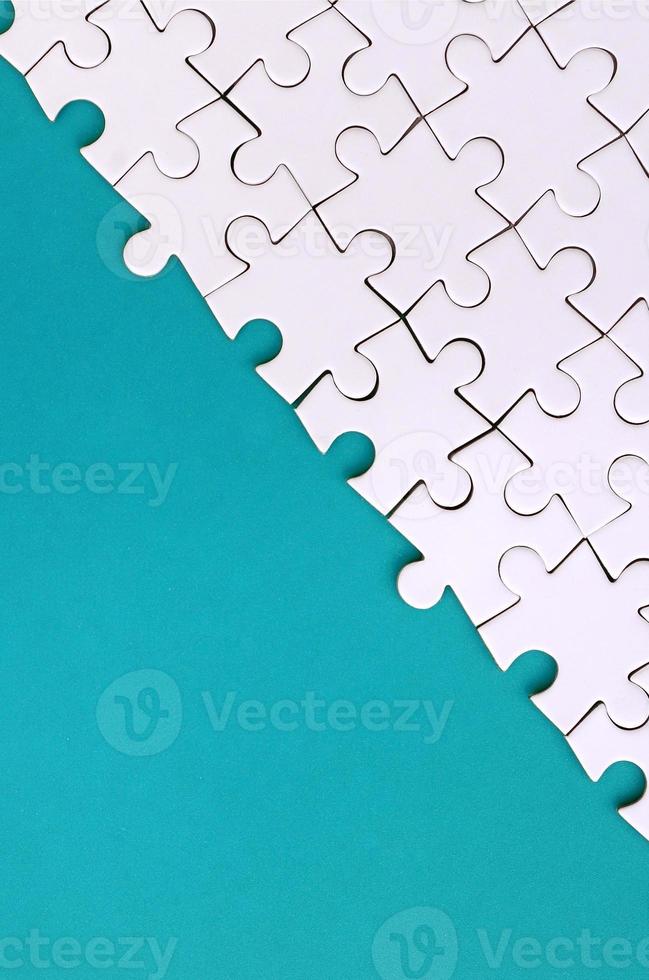 Fragment of a folded white jigsaw puzzle on the background of a blue plastic surface. Texture photo with copy space for text