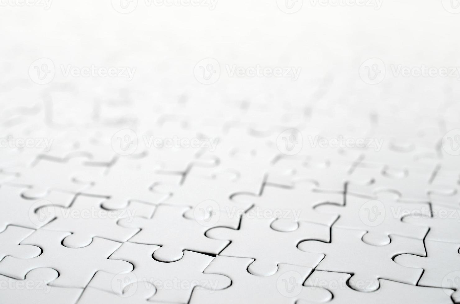 Close up of a white jigsaw puzzle in assembled state in perspective. Many components of a large whole mosaic are united photo