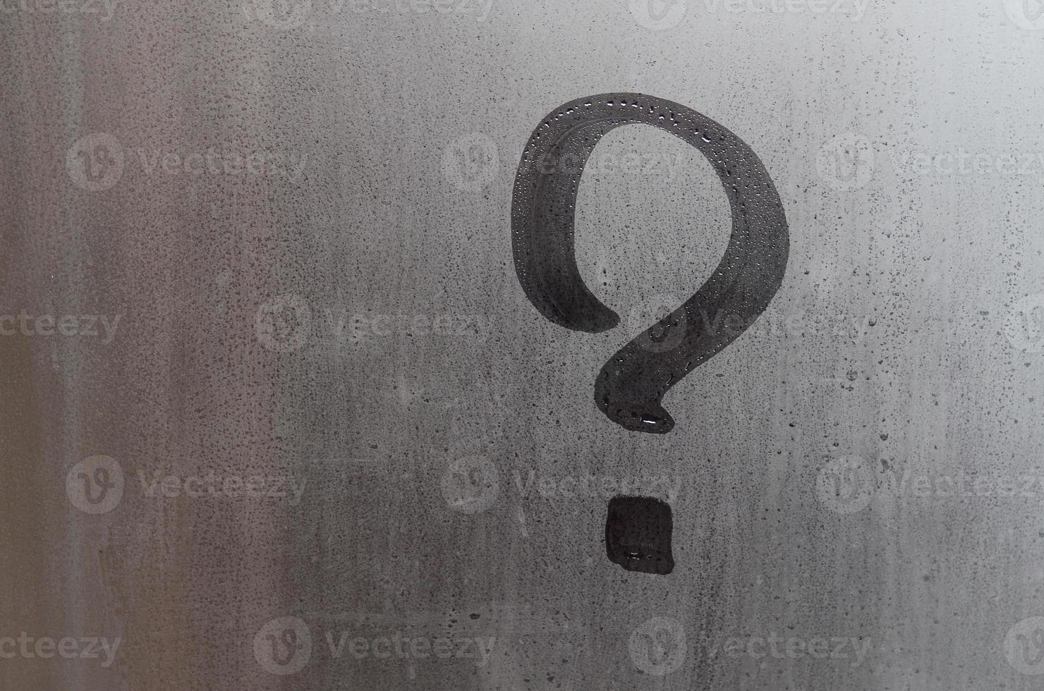 The inscription on glass, question mark concept. Question sign is painted on the surface of misted and wet window photo