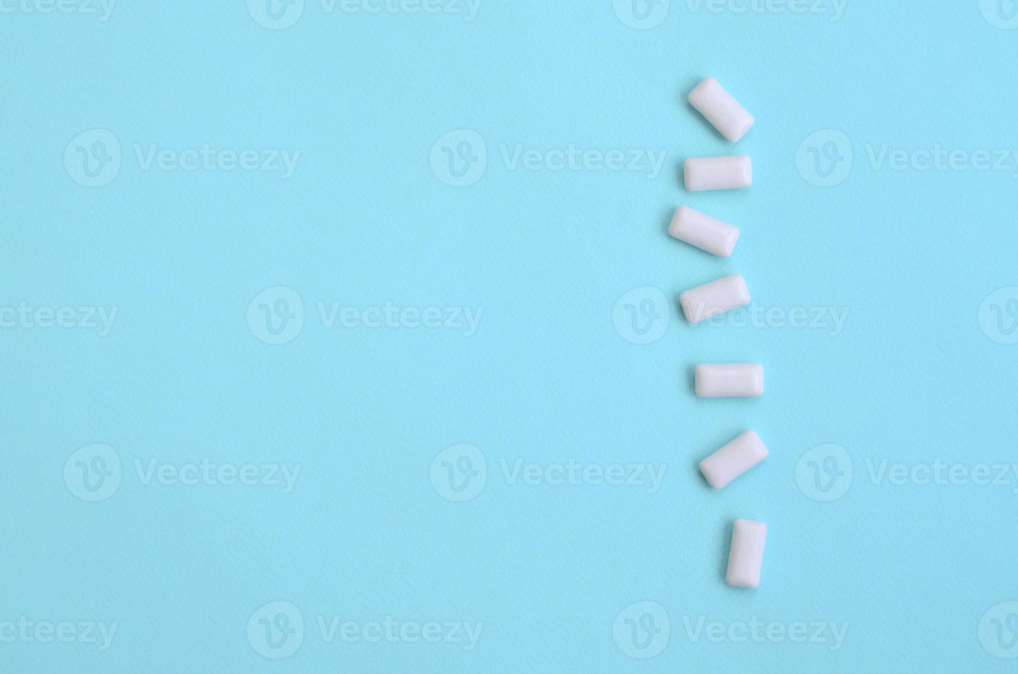 A few chewing gums lie on texture background of fashion pastel blue color paper in minimal concept photo