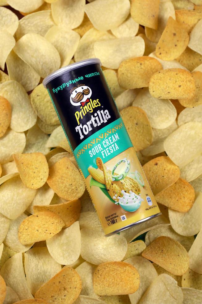 KHARKOV. UKRAINE - MAY 2, 2019 Pringles sour cream fiesta flavour. Cardboard tube can on many Pringles potato chips background. Pringles is a brand of snack chips owned by Kellogg Company photo