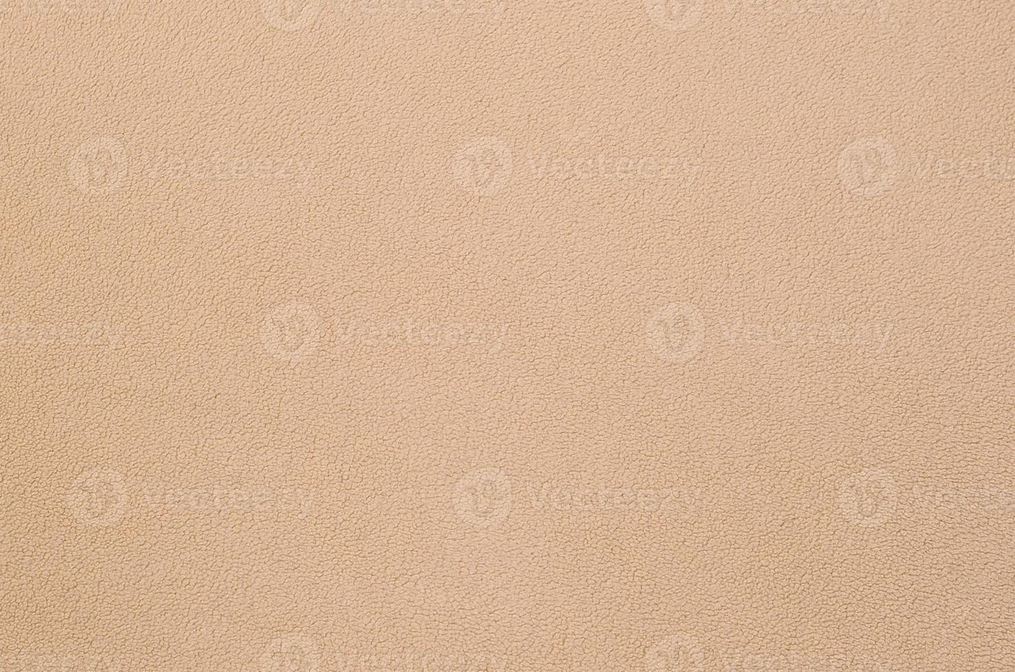 The blanket of furry orange fleece fabric. A background texture of light orange soft plush fleece material photo
