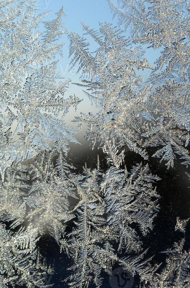 Snowflakes frost rime macro on window glass pane photo