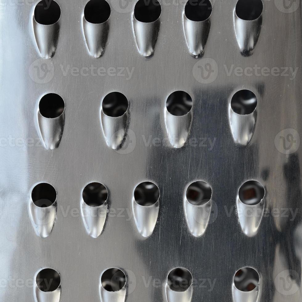 A fragment of a metal chrome grater close-up. Texture of blades for grinding food photo
