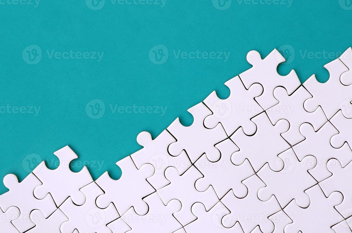 Fragment of a folded white jigsaw puzzle on the background of a blue plastic surface. Texture photo with copy space for text