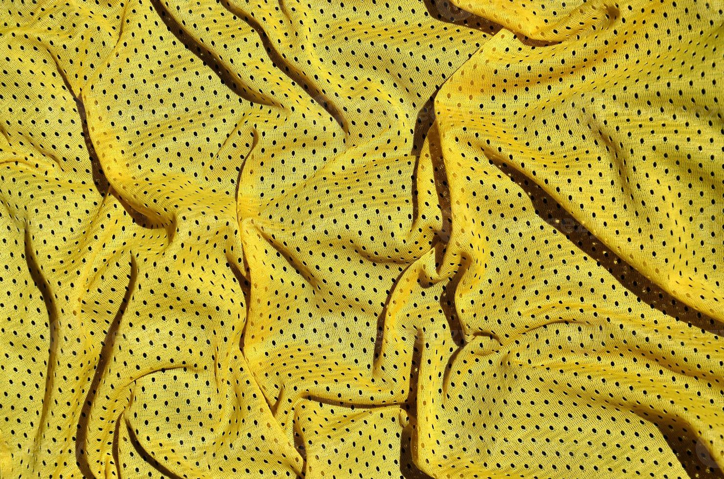 Sport clothing fabric texture background. Top view of yellow polyester nylon cloth textile surface. Colored basketball shirt with free space for text photo